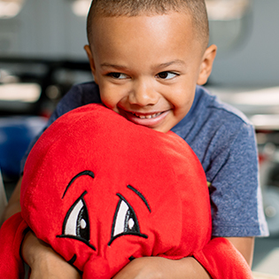 Young child hugs a stuffed animal.