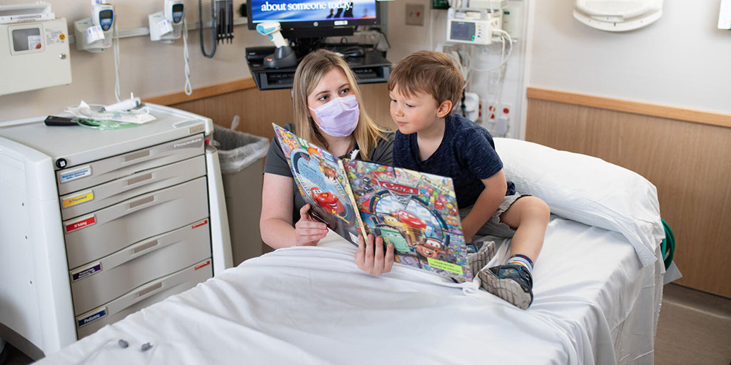 Emergency medicine resident reads to a pediatric patient