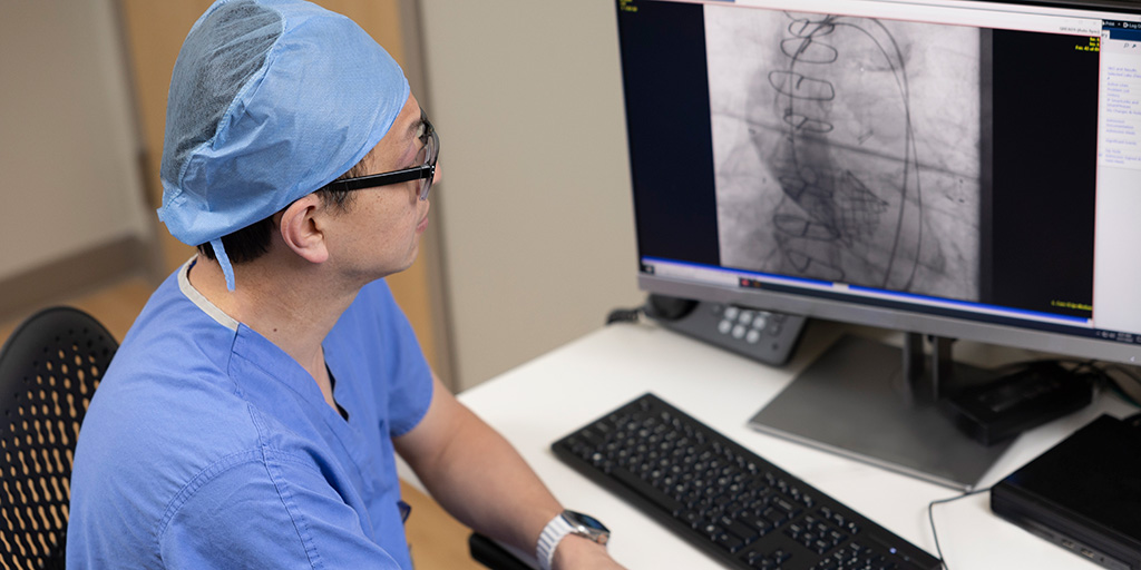A person sat a computer desk looking at patient information.