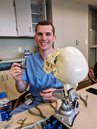 Plastic surgery resident working with a skull model.