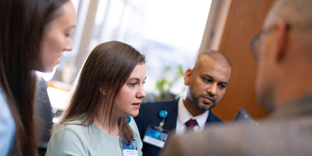 Four people gathered in an office to review medical information on a computer screen.